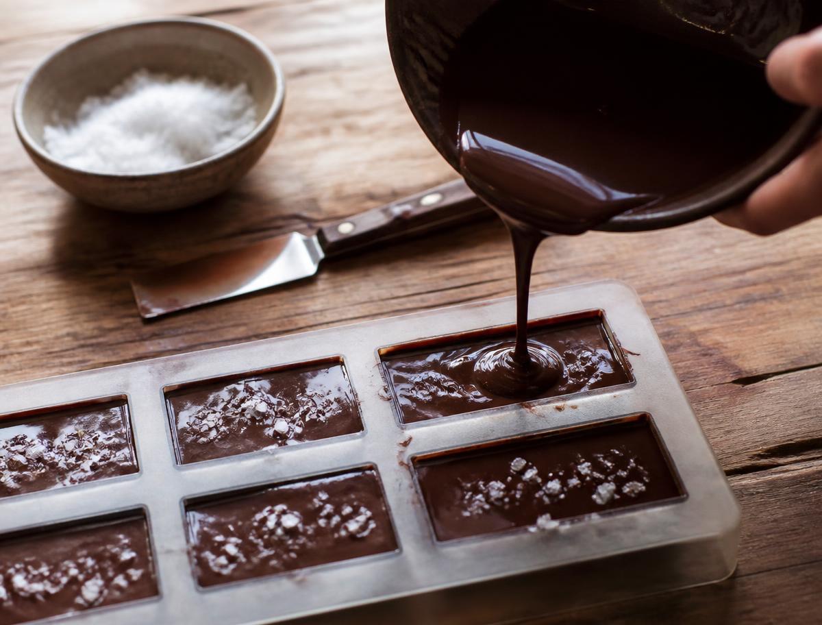 Flydende chokolade hældes i forme og drysses med flager af havsalt