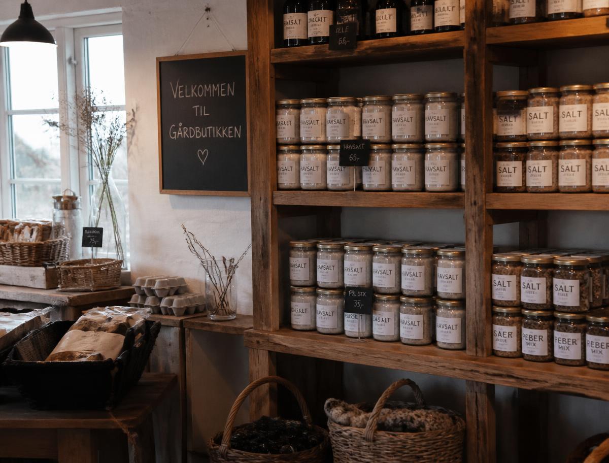 Gårdbutikkens træhylder fyldt med glas med havsalt og lokale specialiteter